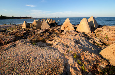 Seascape. Rocks and concrete pyramids against the background of the Lighthouse and the Shabla Bridge. Northern Black Sea Coast, Bulgaria.