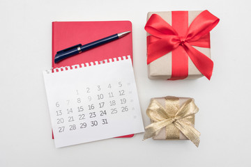 Calendar, pen and notebook, two gifts, white desktop, background, copy space, for recording, close up, top view