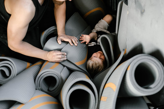 Laughing?boy with man among rolled mats