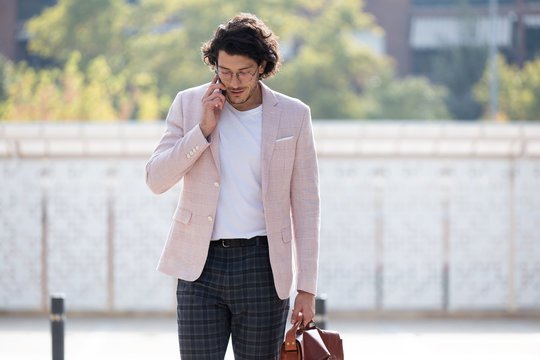 Proud young businessman talking with mobile phone in the street.