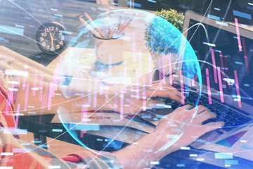 Double exposure of stock graph with businessman typing on computer in office on background. Concept of hard work.