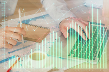 Forex graph with businessman working on computer in office on background. Concept of hardworking. Double exposure.