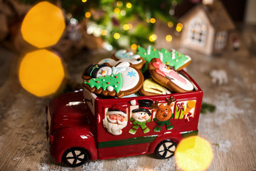Holiday traditional food bakery. Decorative toy car with christmas Gingerbread cakes in cozy warm decoration with garland lights