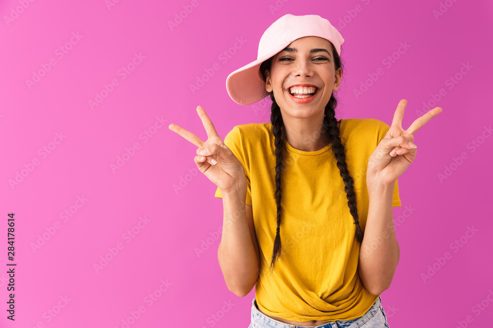 Sticker photo of funny joyful woman wearing cap smiling and showing peace sign