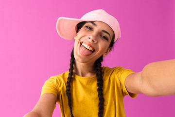 Photo of attractive joyful woman wearing cap smiling and showing her tongue at camera