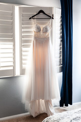 Bridal dress hanging in the room on a ceremony day in the morning