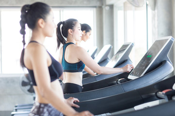 Fototapeta na wymiar Group of women working out on treadmill at sport gym doing cardio