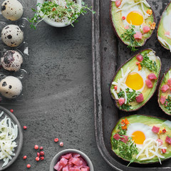 Keto diet dish: Avocado boats with ham cubes, quail eggs, cheese and pepper on dark