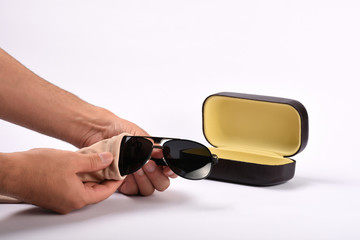 Male hands cleaning sunglasses with microfiber cloth