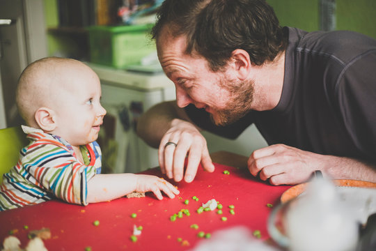 Father feeding his baby son with green peas