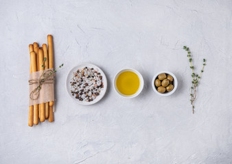 italian grissini stick bread with salt, olive oli and thyne on white beton table