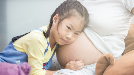 Adorable asian girl touching on pregnant belly mother