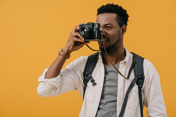 african american man covering face with digital camera isolated on orange