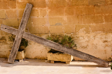 A large wooden cross lies propped up against a wall outside a house in Gozo, Malta.