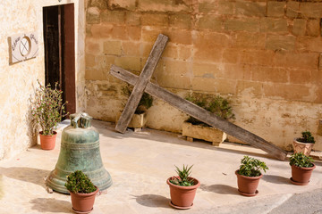 A large wooden cross lies propped up against a wall outside a house in Gozo, Malta.