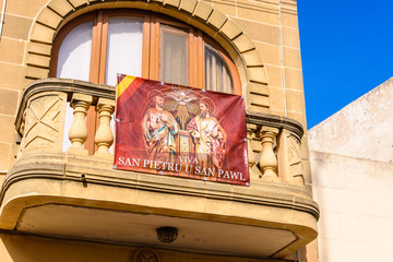 A banner with Saint Peter and Saint Paul hangd from the balcony of a house in preparation for a...