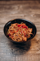 Udon noodles in a black plate on a wooden table