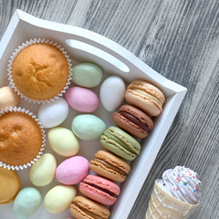 Easter flat lay with macarons, muffins and marzipan eggs jn a de