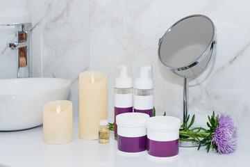 Set of natural cosmetics in beauty salon. Jars and bottles of body or hair care product on table with flowers. Space for text