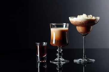 Coffee cocktails and liquor on black reflective background.
