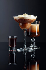 Coffee cocktails and liquor on black reflective background.