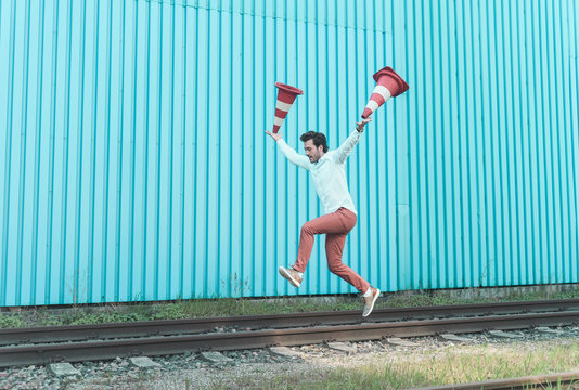 Young man jumping on rails, balancing traffic cones