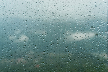 Rain drops on window glasses surface with cloudy background . Natural Pattern of raindrops isolated on cloudy background.