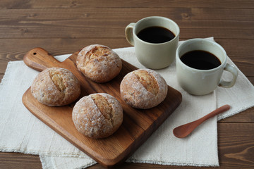 まな板にのせたフランスのパン ライ麦パン ホットコーヒー 木のテーブル