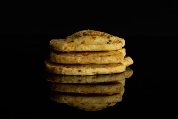 Group of three whole savory cheese palmier isolated on black glass