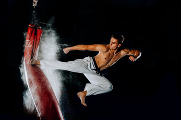Man hitting the punching bag on black background