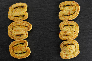 Group of six whole crisp savory cheese palmier flatlay on grey stone