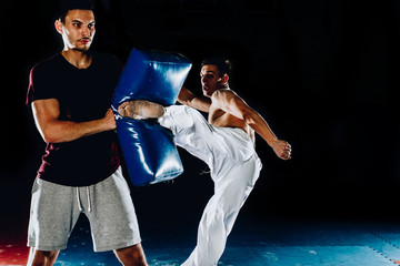 Young caucasian sportsman kicking punching bag