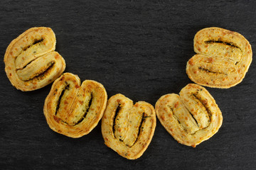 Group of five whole baked savory cheese palmier flatlay on grey stone
