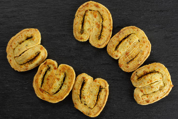 Group of six whole fresh baked savory cheese palmier flatlay on grey stone