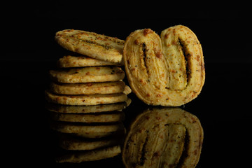 Group of six whole savory cheese palmier isolated on black glass