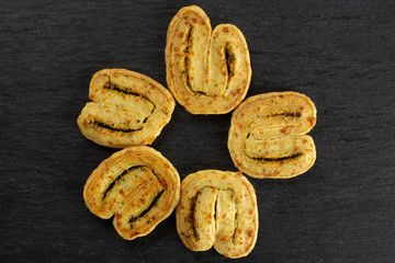 Group of five whole savory cheese palmier flatlay on grey stone