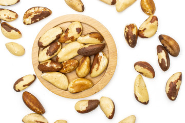 Lot of whole single unshelled brazil nut on bamboo plate flatlay isolated on white background