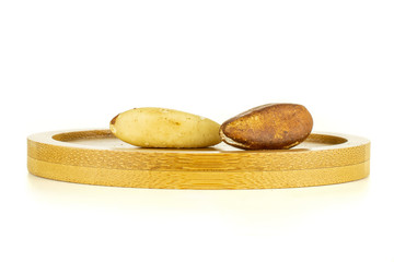Group of two whole unshelled brazil nut on bamboo plate isolated on white background