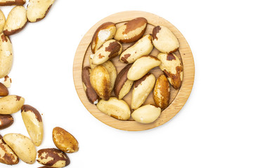 Lot of whole unshelled brazil nut on bamboo plate flatlay isolated on white background