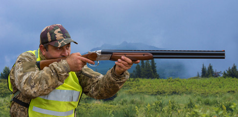Hunter with a hat and a gun in search of prey in the steppe against the backdrop of a mountains