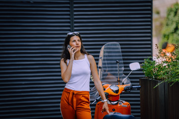 Fototapeta na wymiar Cheerful woman talking on the phone outdoors and looking away