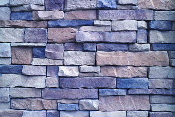 Front view of rough stone wall in purple blue color gradation