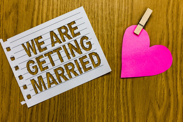 Conceptual hand writing showing We Are Getting Married. Business photo showcasing Engagement Wedding preparation Loving couple Yellow woody deck word with white page paper clip grip heart