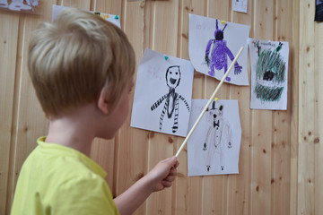 The child talks about his drawings. Pictures are fixed on the wall. The girl shows the drawings...