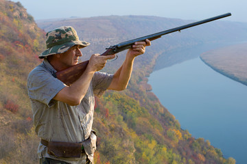 Fototapeta premium Hunter with a german drathaar and spaniel, pigeon hunting with dogs against the backdrop of a beautiful evening lake. 