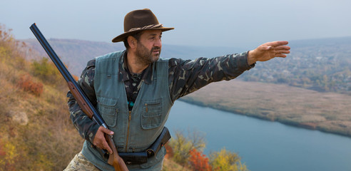 Hunter with a german drathaar and spaniel, pigeon hunting with dogs against the backdrop of a beautiful evening lake.	