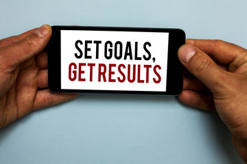 Word writing text Set Goals, Get Results. Business concept for Establish objectives work for accomplish them Human hand hold smartphone with red and black letters on shadow blue floor