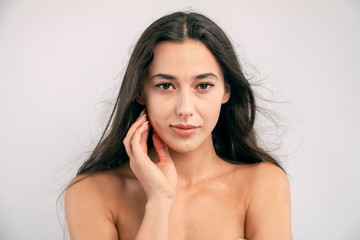 Portrait of young brunette model with brown eyes and naked shoulders looking at camera isolated...