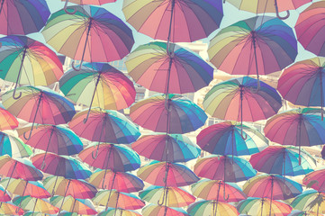Fototapeta na wymiar Street decorated with colored and open umbrellas. Blurred pastel background for your text.