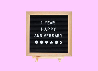 Closeup a board with 1 year happy anniversary word isolated on pink background
